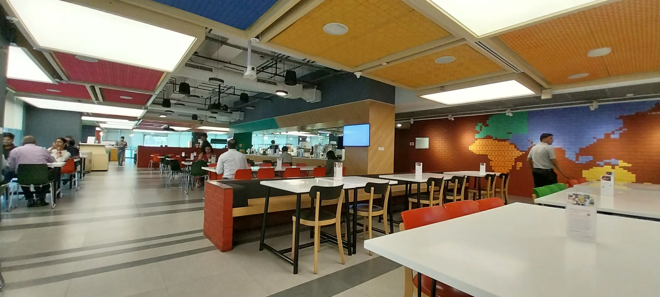 Colorful modern office cafeteria with pixel-art wall mural and casual seating