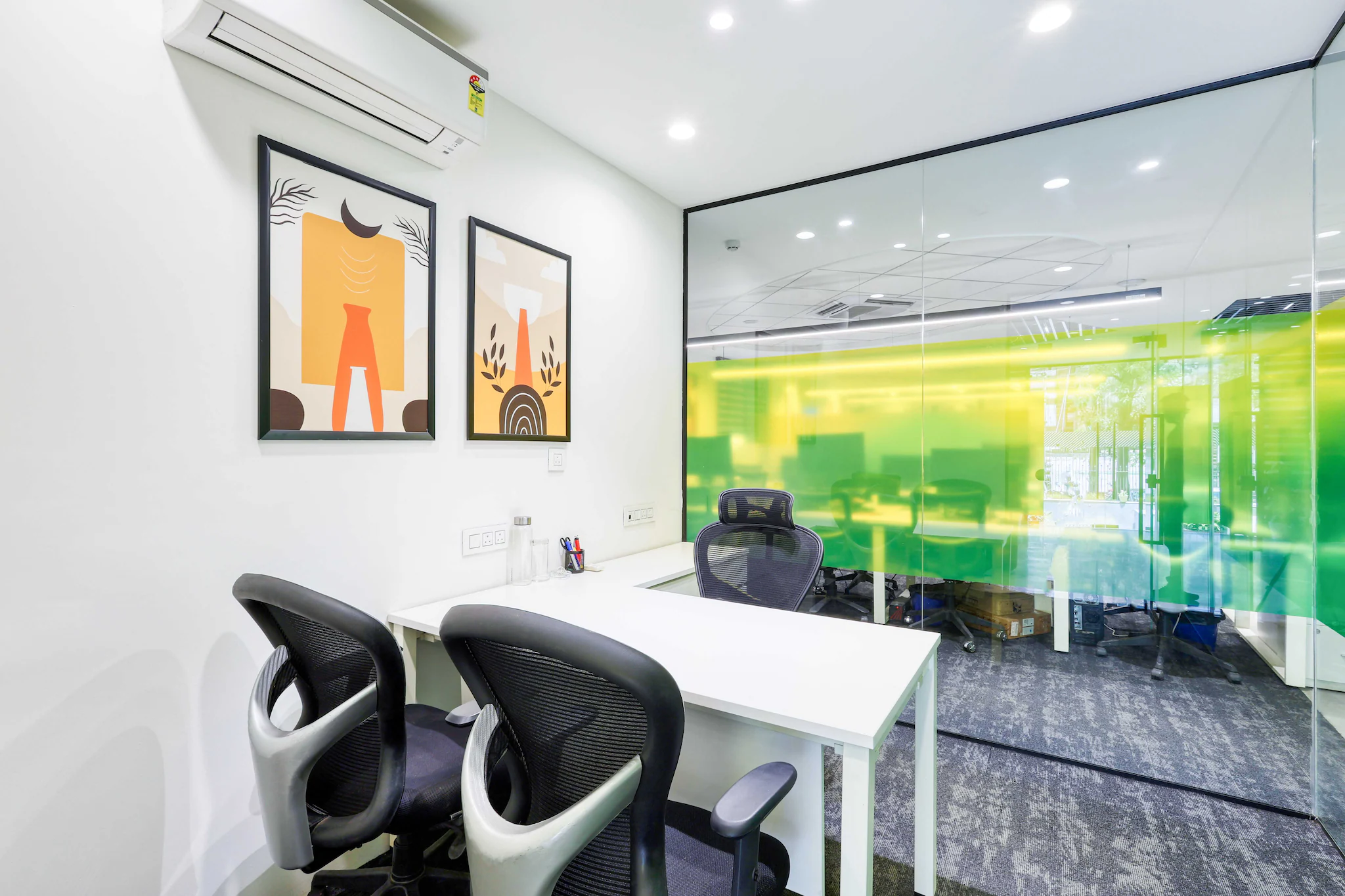 Small private office room with a white desk and colour-tinted glass wall